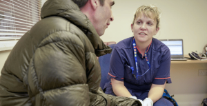 Nurse talking to a man wearing a green puff jacket