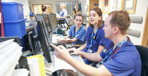 Mjekët dhe infermierët duke parë një ekran kompjuteri në një A&E të zënë