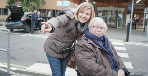 Picture of an old man in a wheelchair with a woman pointing at something in the distance