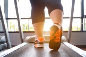 Legs of obese person walking on a treadmill