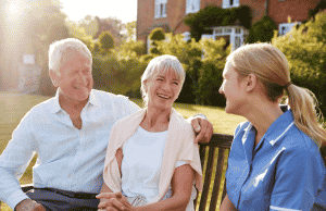 Nurse sitting on bench outside with older couple
