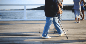 Person walking along a pier using a crutch for support